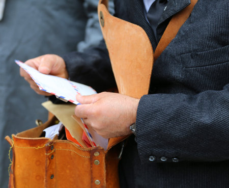 postman with the old bag full of letters while delivering mail in the city