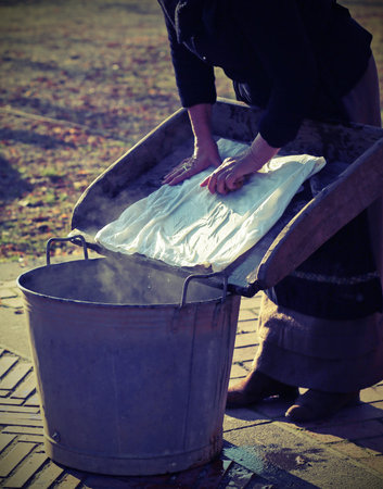 elderly does the laundry in an old board with bowl