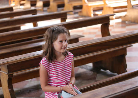pretty little girl on Pew in the church during a prayerの写真素材
