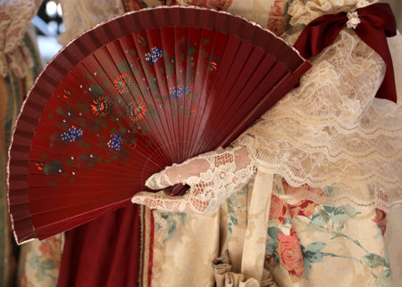 elegant woman with an ancient ceremonial dress and the fan in her hand with white gloveの写真素材