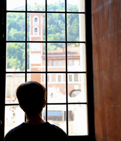 child looks from a windows the ancient tower in Italyのeditorial素材