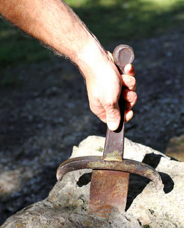 Excalibur sword in the stone and the hand of man in th woodの写真素材