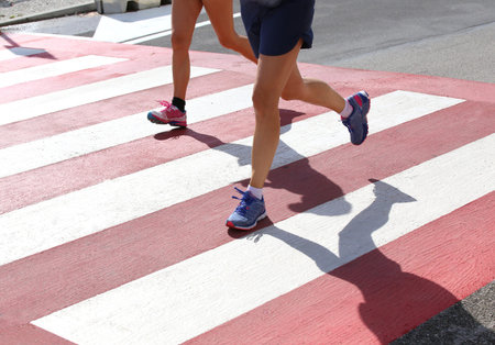 runners during a marathon race in the city on a pedestrian crossing with red and white stripes
