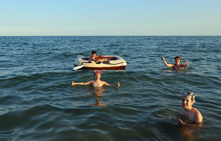 family with three children and a dinghy to play in summerの写真素材
