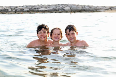 three friendly brothers swimming in the sea during summer vacation and little girl whit diving mask in the adriatic seaの写真素材