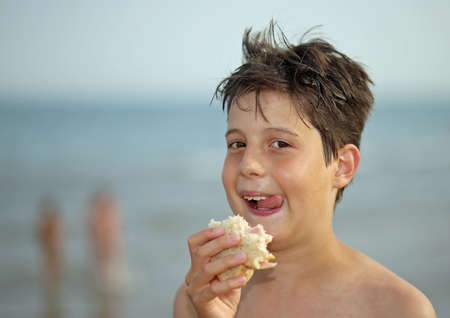 nice guy while eating a sandwich on the beach in summerの写真素材