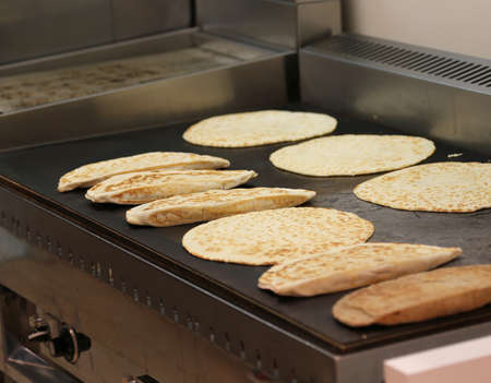 many stuffed bread called piadina romagnola on hot griddle typical dish in Italyの写真素材