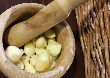 handcrafted wooden pestle with garlic cloves to prepare the Pesto alla Genovese a typical Italian dishの写真素材