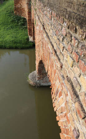 detail of a medieval bridge made of red brick on the river in Europeの写真素材