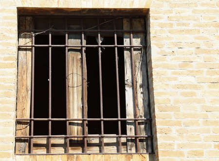 broken window of an abandoned house with iron bars and broken glassの写真素材
