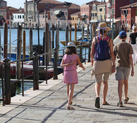 family with mom and two children walking on the island of Murano near Venice in Italyの写真素材