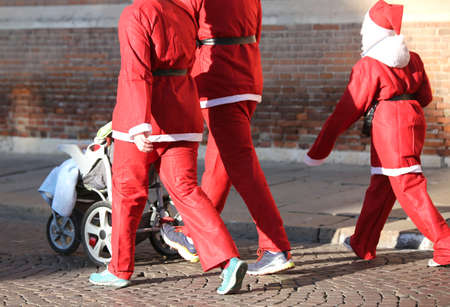 Family with Santa Claus clothes walks with the stroller at Christmasの写真素材