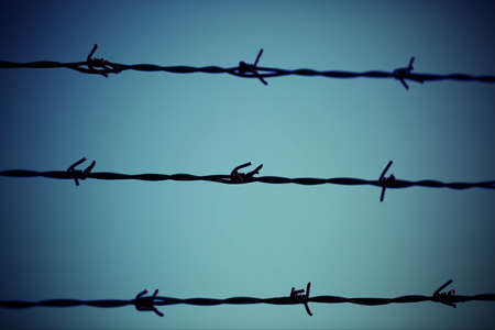 three barbed wire lines blur and light blue blurred backgroundの写真素材