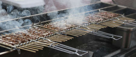 skewers of grilled meat with a lot of smoke in a street food stallの写真素材