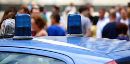 two blue lights of an italian police car and many peopleの写真素材