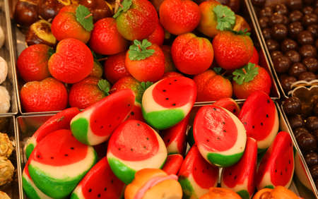 Fruit-shaped marzipan in baskets that look like slices of watermelon and strawberries for sale at marketの写真素材