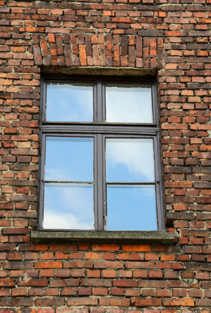 old brick wall with a window and the reflection of the skyの写真素材