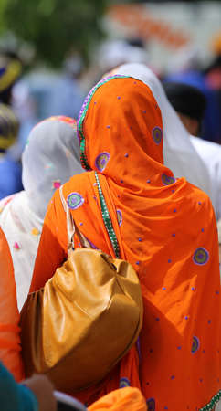 woman with orange veil headdress during a gathering of people in the cityの写真素材