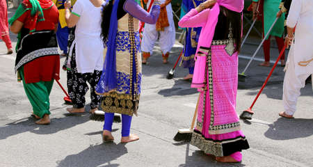 barefoot women with colorful clothes sweep the asphalt road during the event in the cityの写真素材