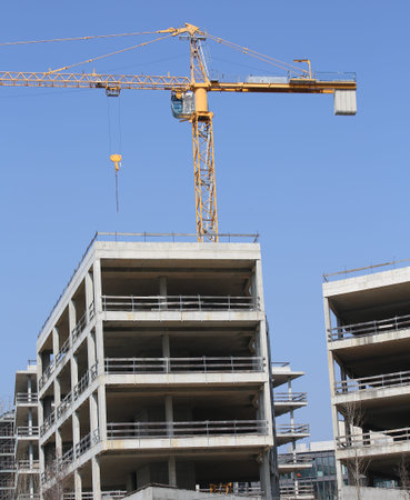 building under construction with concrete walls and a yellow crane