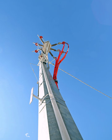 big pole of an electrical system with cables and high voltage insulators of a voltage transformer
