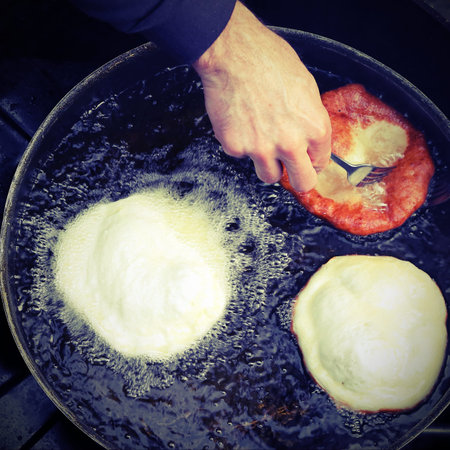 hands of cook frying three pancakes in a pan of hot oil in a street food standの写真素材