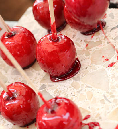 red apples with caramelized sugar syrup and the wooden stick to eat itの写真素材