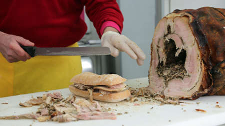 hand of chef slicing the meat of pork to prepare a sandwich in the food stall on the streetの写真素材