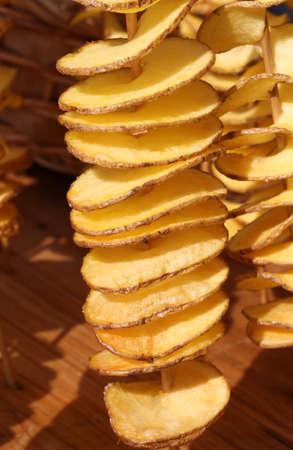strret food fried sliced potatoes stuck in the wooden skewer for sale in the standの写真素材