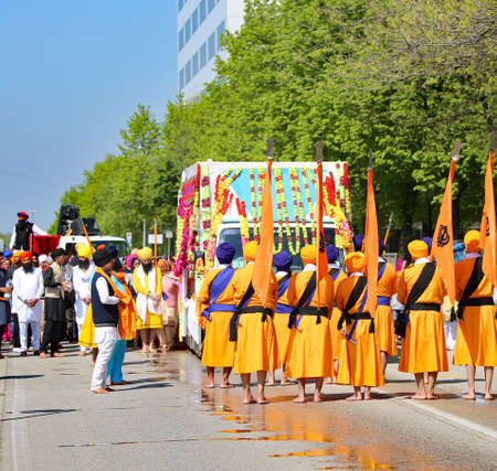 Vicenza, VI, Italy - April 8, 2017: barefooted men with turbans and scimitars and orange flag at the ceremony of the Sikh religionのeditorial素材