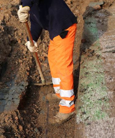 man at work in the trench in the roadwork with the shovel inside