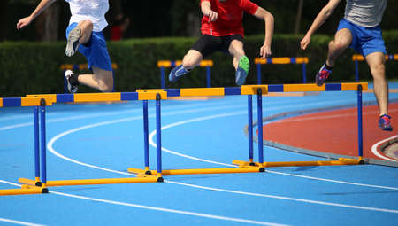 Hurdle race, three boys jumping over hurdles in a running trackの写真素材