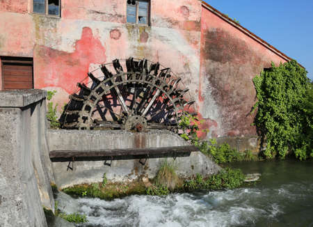 big wheel of an old abandoned water mill and the riverの写真素材