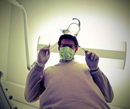 dentist with green health mask and tooth care equipment in the dental clinic with fisheye lensの写真素材