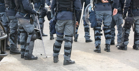 group of police officers in riot control with batons during security checks on the streets of the...