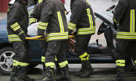 Four brave firemen transport the injured with a stretcher far from the accident site to make it safeの写真素材
