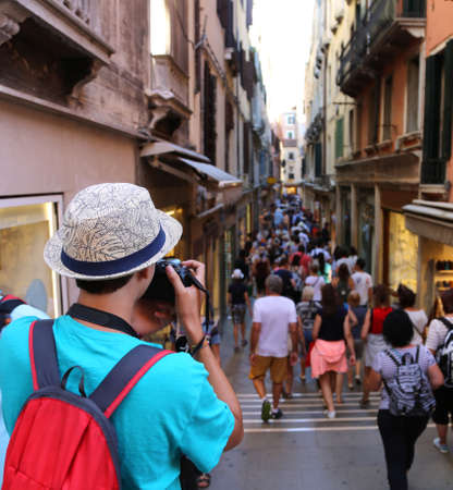 Young photographer takes a picture to people walking in the pedestrian zoneの写真素材