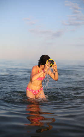 Little girl with diving mask while playing on sea waterのeditorial素材