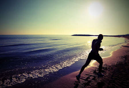 Man runs very fast on the beach at dawn in backlight with lomo photograph effectの写真素材