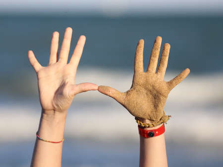 ten fingers and two hands of a child on the beach near the seaの写真素材