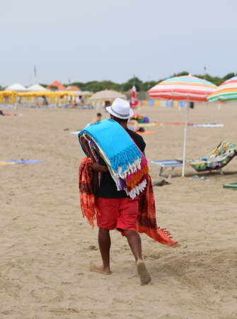 Abusive walker walking on the sandy beach selling cotton fabrics in summerの写真素材