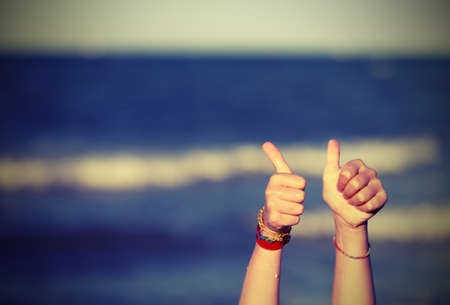 Thumbs up to tell OK and the background of the sea with vintage effectの写真素材