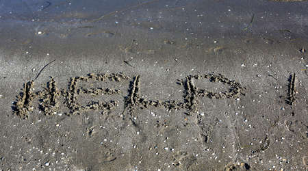 huge HELP text on sand by the seaの写真素材