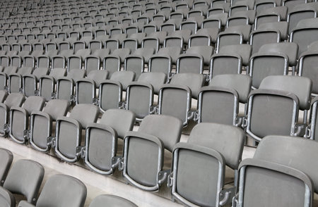 lots of reclining chairs on the stadium bleachers with no people before the sporting event