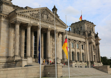 Reichstag building is Parliament of Germany with flag at half mast. The big dedication text  over...