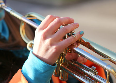 hand of young woman playing the trumpet in the music band during the sound performance