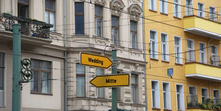 two yellow road signs with the arrow and the indications of the most important districts of Berlin in Germanyの写真素材