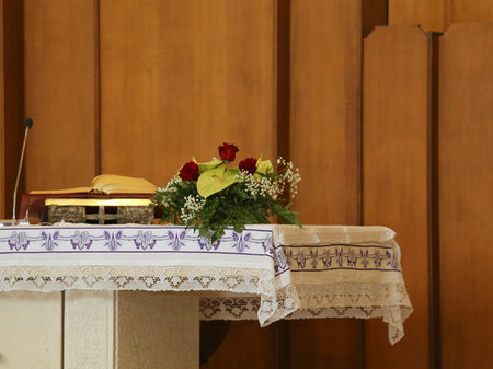 altar of a Christian church with the bible and the vase of flowers during the celebration of the...