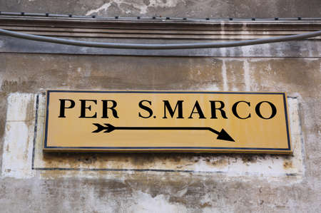 Yellow Street sign in Venice in Italy with directions to Square of Saint Markの写真素材