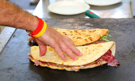 cook while baking the piadina that means flat bread in italian language on the hot plate in the street food standの写真素材